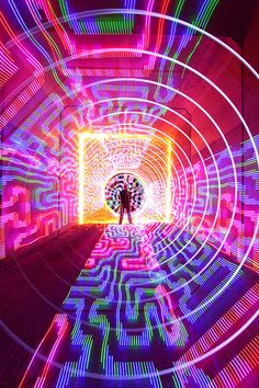 a person standing in a tunnel with colorful lights