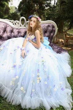 a woman sitting on top of a purple couch wearing a blue and white wedding dress