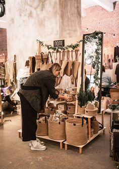 a woman standing in front of a table filled with baskets