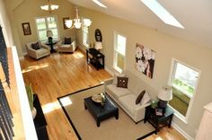 an aerial view of a living room with hardwood floors and white furniture, including couches