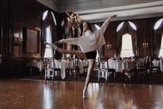 a woman is dancing on the dance floor in a large room with tables and chandeliers