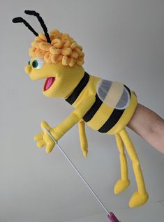 a hand holding a stuffed toy bee on top of a stick