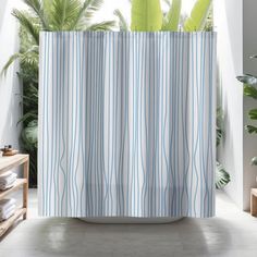 a shower curtain with blue and white stripes on it in front of a window next to a potted plant