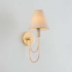 a wall light with a white shade on it's side and a lamp attached to the wall