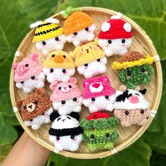 small crocheted toy animals sitting on top of a bamboo plate in front of green leaves