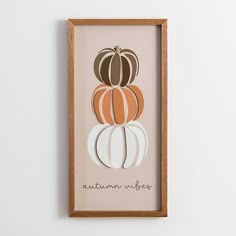 an orange and white pumpkin sitting on top of a wooden framed wall mounted art piece