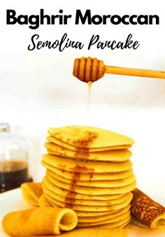 stack of pancakes with honey being drizzled over them on a white plate