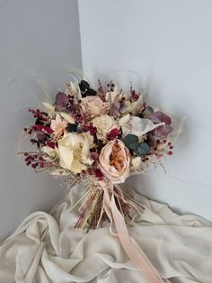 a bouquet of flowers sitting on top of a white cloth next to a gray wall