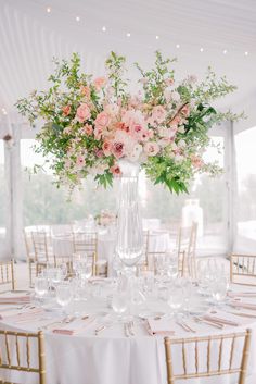 a vase filled with lots of flowers on top of a white table cloth covered table