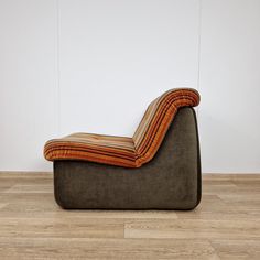 a brown couch sitting on top of a wooden floor next to a white wall and wood floors