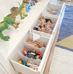 the toy dinosaurs are lined up on the counter in the kitchen and ready to be put into their bins