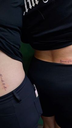 two women with tattoos on their stomachs, one has the word love written in cursive writing