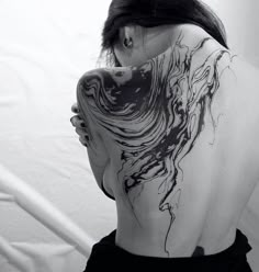 a woman's back is covered in black and white ink