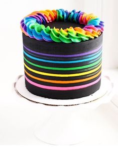 a multicolored cake sitting on top of a white table next to a window