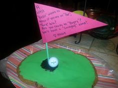 a cake with a golf ball on it and a pink flag sticking out of the hole