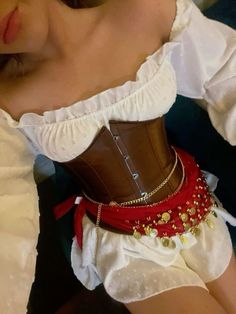 a woman wearing a corset with red and gold beads