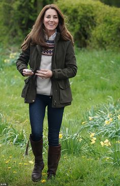 a woman standing in the woods wearing a brown jacket