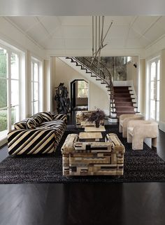 a living room filled with lots of furniture next to a stair case in front of a window