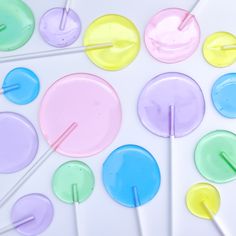 several different colored lollipops are arranged on a white surface with pins sticking out of them