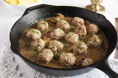 a skillet filled with meatballs and gravy on top of a table