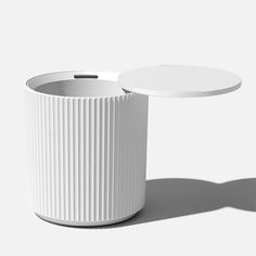 a white vase sitting on top of a table next to a round tray with a lid