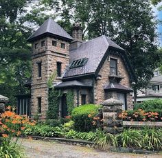 an old stone house surrounded by flowers and trees