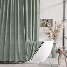 a bath tub sitting next to a window covered in green curtaining and a plant