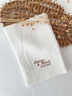 two white napkins with embroidered names on them sitting next to each other in front of a woven basket