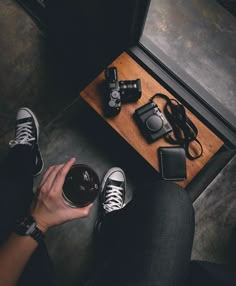 a person sitting on the floor with their feet up next to a camera and cell phone