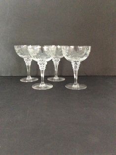 four wine glasses sitting on top of each other in front of a gray wall and floor