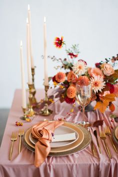 the table is set with candles, plates and napkins for an elegant dinner party