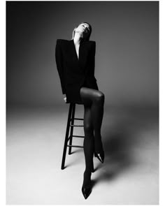 a woman sitting on top of a stool wearing tights and heels with her legs crossed