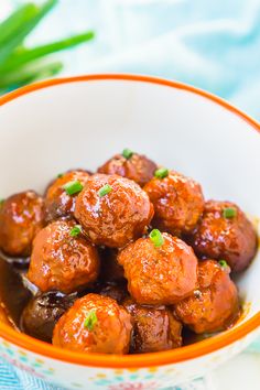 a bowl filled with meatballs covered in sauce and garnished with green onions