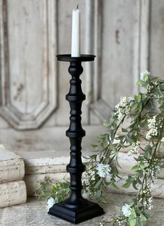 a black candle holder sitting on top of a table next to white flowers and books