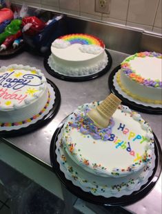 three birthday cakes with rainbow frosting on them