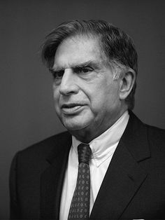 a black and white photo of a man in a suit looking at the camera with a serious look on his face