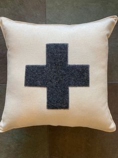 a white pillow with a black cross on the front and blue stitches across the middle