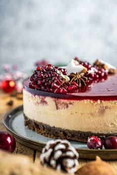 a cheesecake with cranberry topping on a plate next to some pine cones