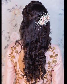 the back of a woman's head with long hair and flowers in her hair