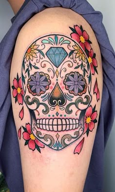 a woman's arm with a colorful sugar skull tattoo on the left side of her body