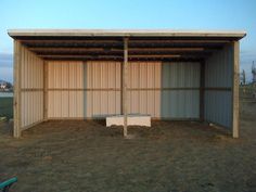 an empty building in the middle of a field with no people around it and one bench on the ground