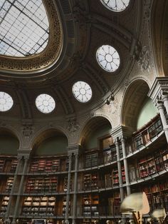 the interior of a large library with many bookshelves and round glass windows on the ceiling