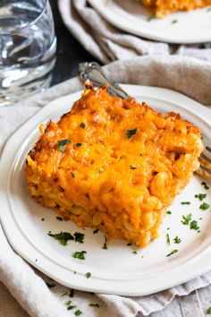 a white plate topped with lasagna covered in cheese and parsley next to a fork