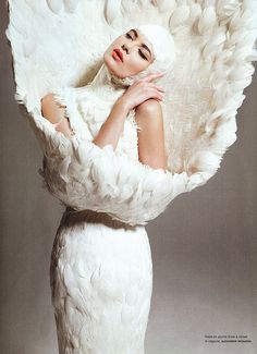 a woman with white feathers on her head is posing for a magazine cover photo shoot