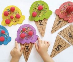 a child's hand is touching some ice cream cones with sprinkles