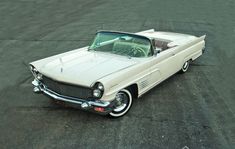 an old white car parked in a parking lot