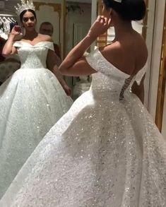 a woman in a wedding dress looking at herself in the mirror while another person takes a selfie