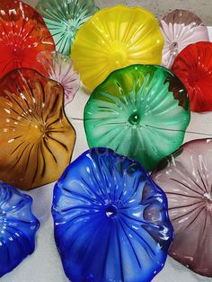 there are many different colored vases on the table together, including one that is shaped like a flower