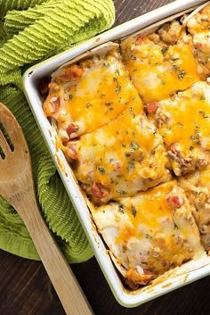 a casserole dish with meat and cheese in it next to a wooden spoon