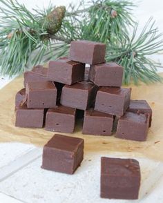 a pile of chocolate squares sitting on top of a cutting board next to pine branches